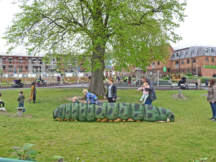 children climbing over caterpillar sculpture